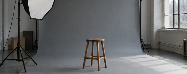 An empty photo studio with a gray paper backdrop and a softbox